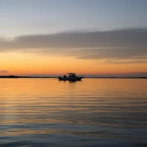 A calm Skull Creek view at dusk with a silhouette of a boat in the distance.